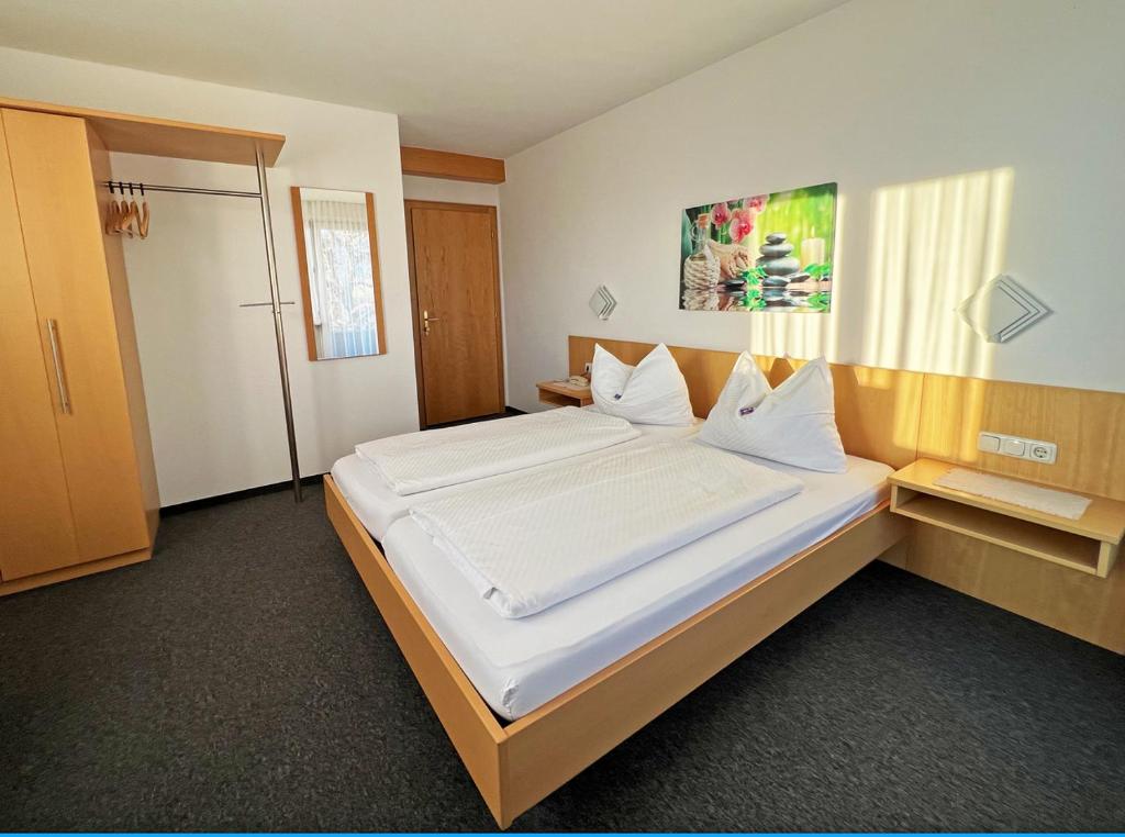 a bedroom with a large bed with white sheets at Hotel-Pension Sternen in Klaus