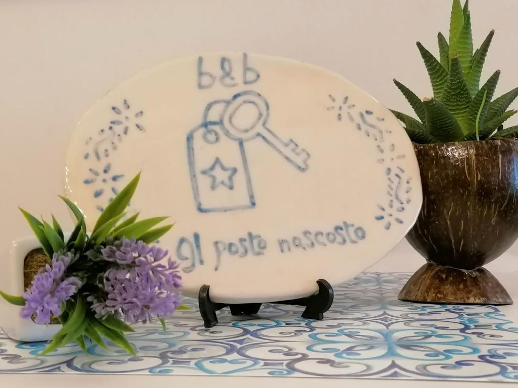un piatto con una chiave sopra, accanto a un vaso con dei fiori. di Il Posto Nascosto a Porto Torres