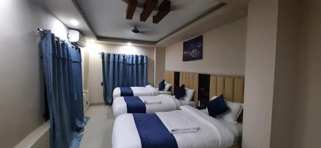 eine Gruppe von 4 Betten in einem Zimmer mit blauen Vorhängen in der Unterkunft Hotel Sara PVT LTD in Janakpur