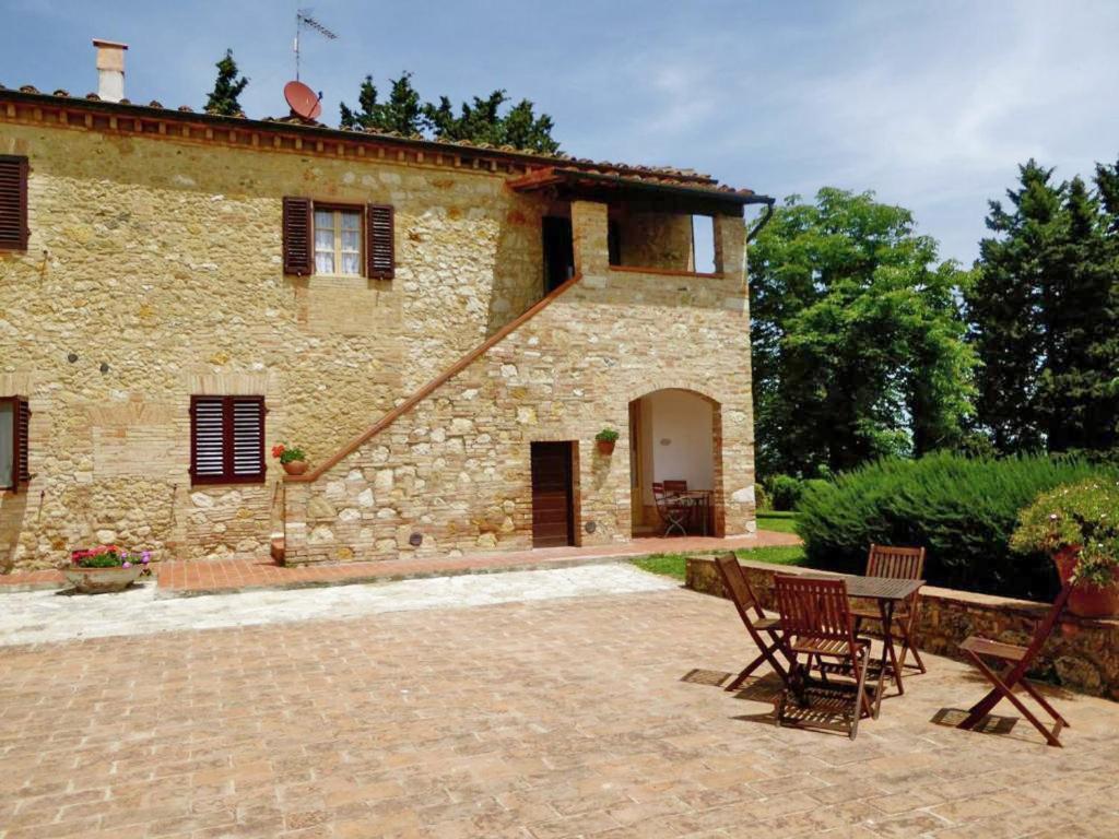 uma casa de pedra com duas cadeiras e uma mesa em Agriturismo Fattoria Il Piano - Appartamento Antica Cucina - San Gimignano em San Gimignano