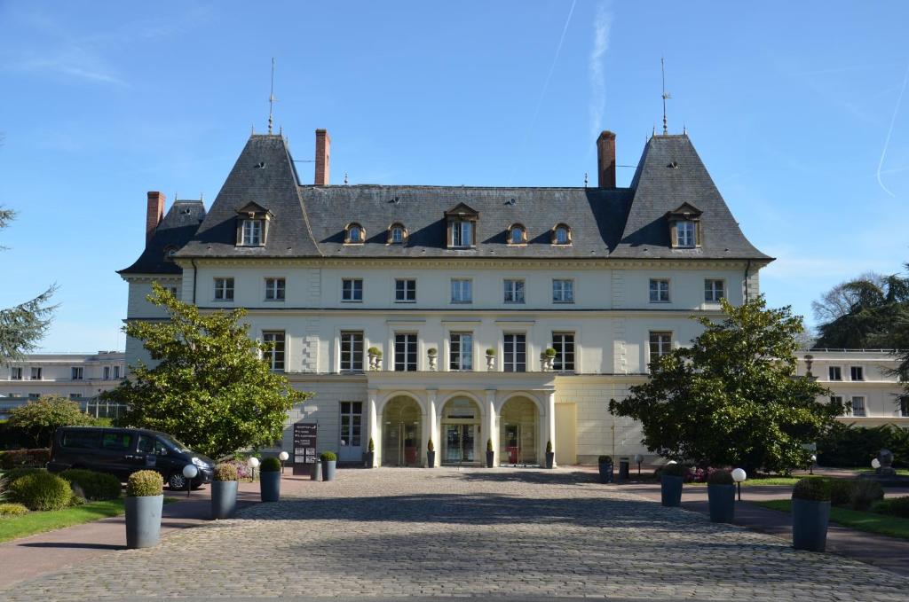 um grande edifício branco com um telhado de gambrel em Domaine de Frémigny em Bouray-sur-Juine