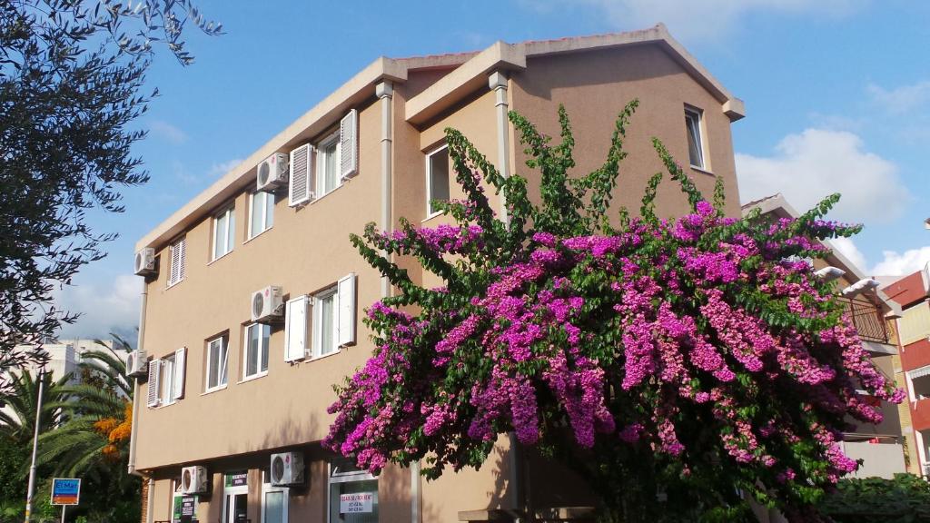 un edificio con flores púrpuras delante de él en El Mar Apartments, en Budva