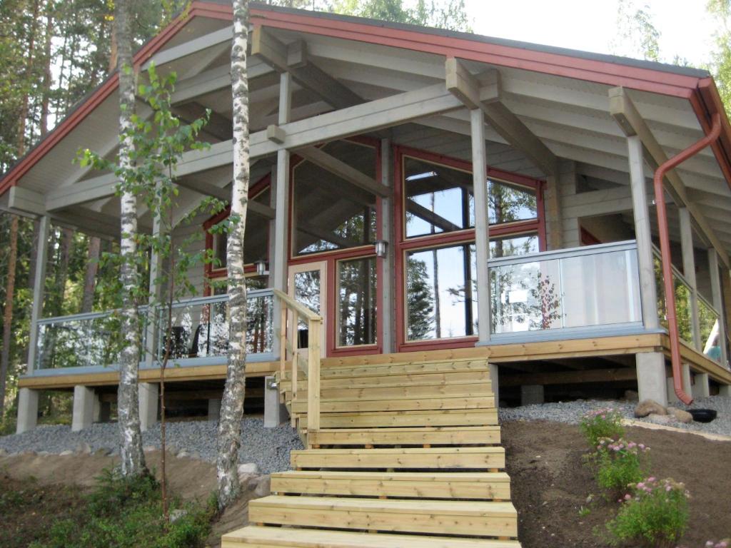 a house in the woods with glass doors and stairs at Villa by the Lake in Joutseno