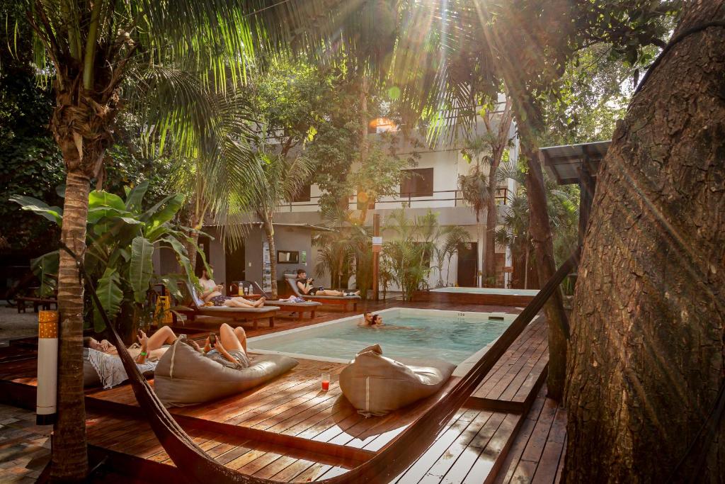 a group of people laying in a hammock by a pool at Che Tulum Hostel & Bar Adults Only in Tulum