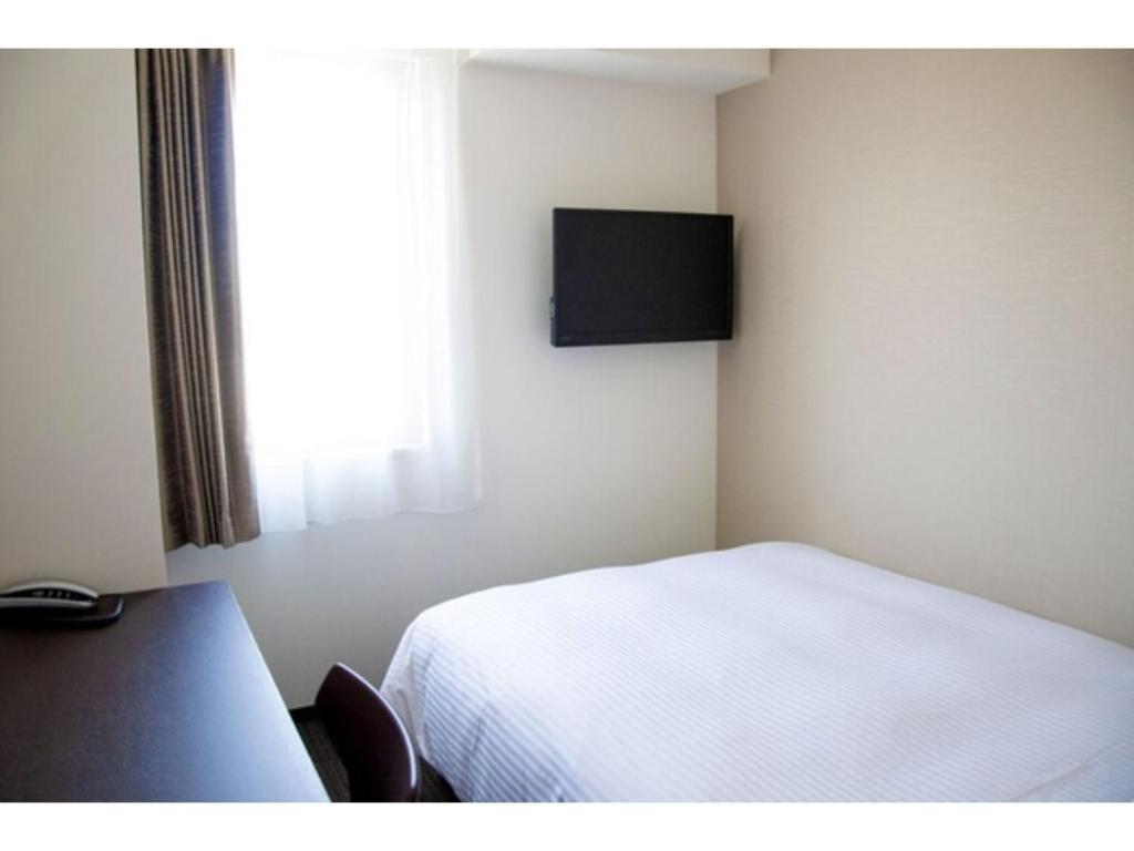 um quarto com uma cama branca e uma janela em HOTEL GLANY's KUMAGAYA - Vacation STAY 27265v em Kumagaya