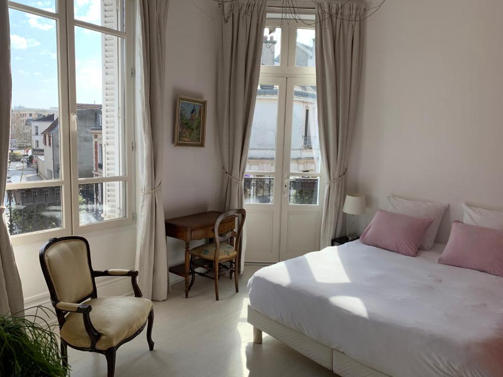 a bedroom with a bed and a chair and windows at Le Saint-Rémy in Épernay