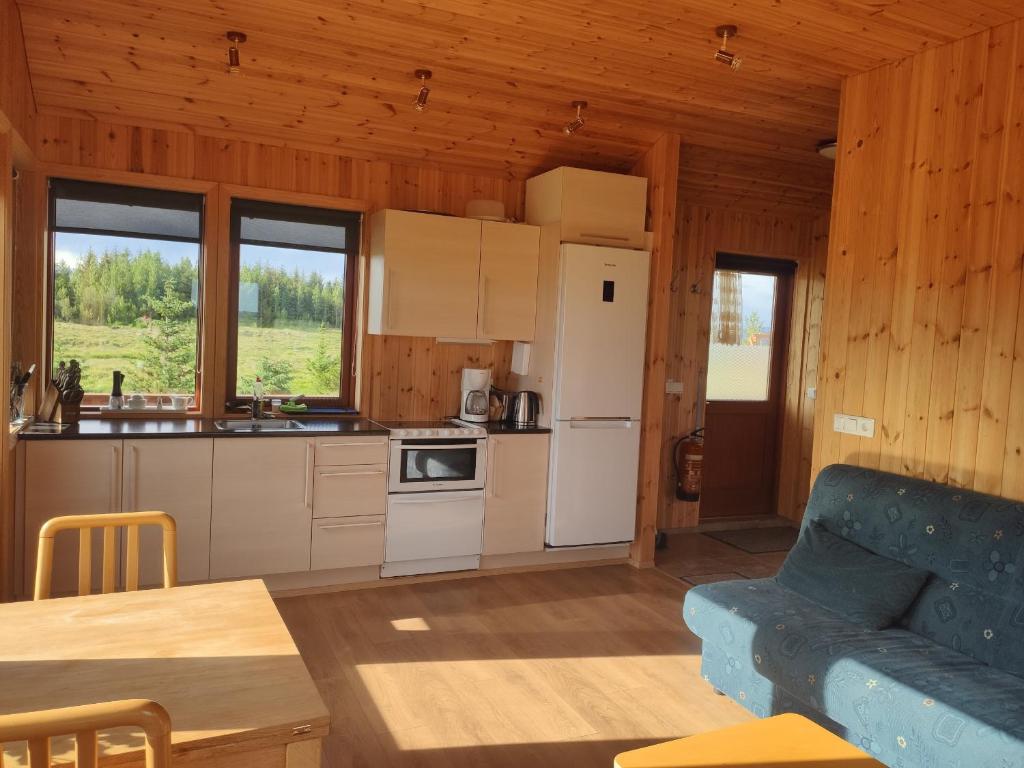 una cocina con electrodomésticos blancos y un sofá azul en una habitación en Bright and Peaceful Cabin with Views & Hot Tub, en Selfoss