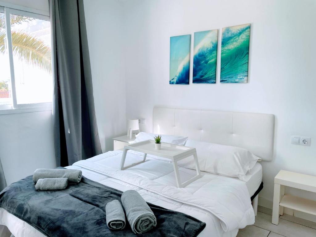 コラレホにあるSinfonia Corralejo iRent Fuerteventuraの白いベッドルーム(白いベッド1台、テーブル付)
