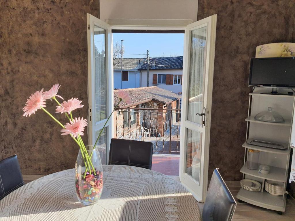 a vase with flowers sitting on a table with a window at La corte delle fate in Lonato