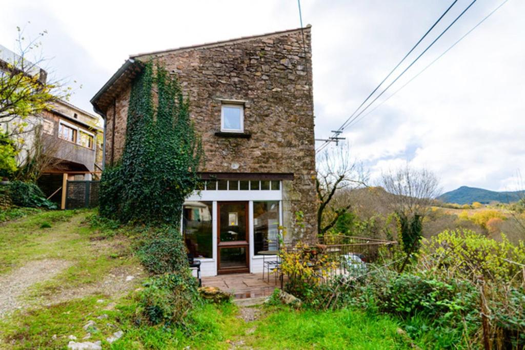 une maison en pierre sur une colline avec une porte dans l'établissement Maison charmante à Faugères avec vue sur la montagne, à Faugères