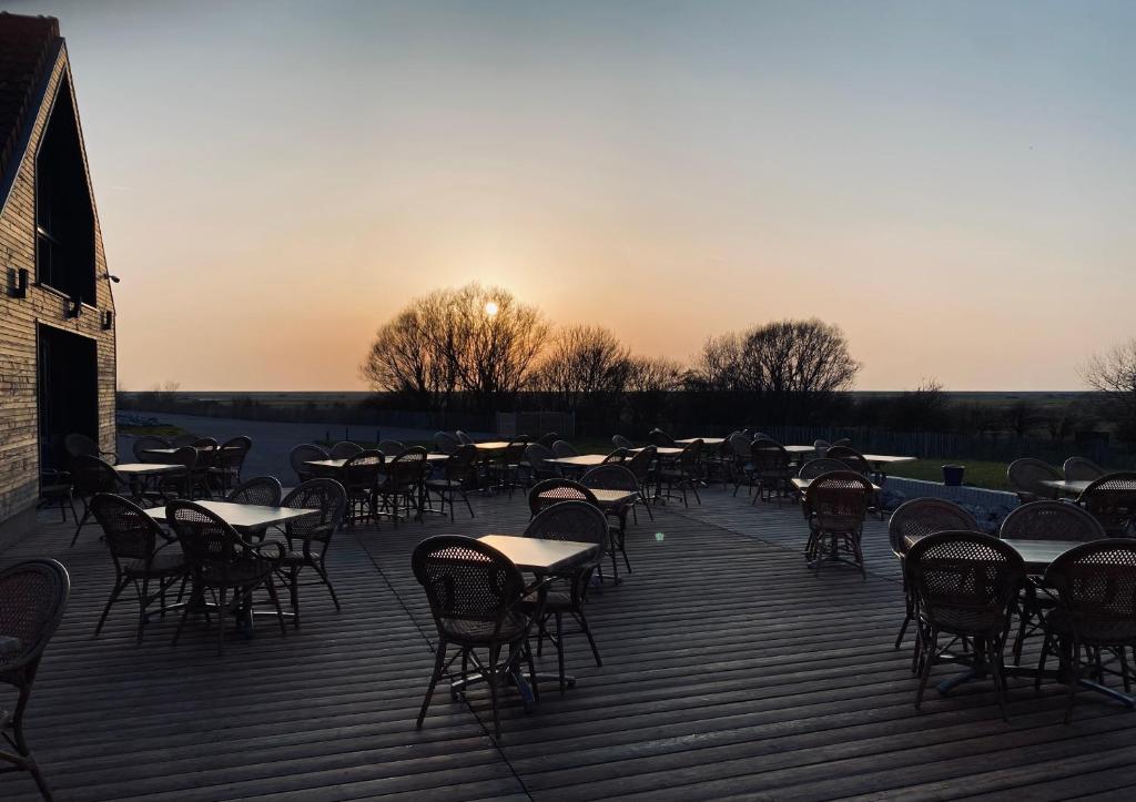 um grupo de mesas e cadeiras num deque com o pôr-do-sol em Domaine de la Mer em Woignarue