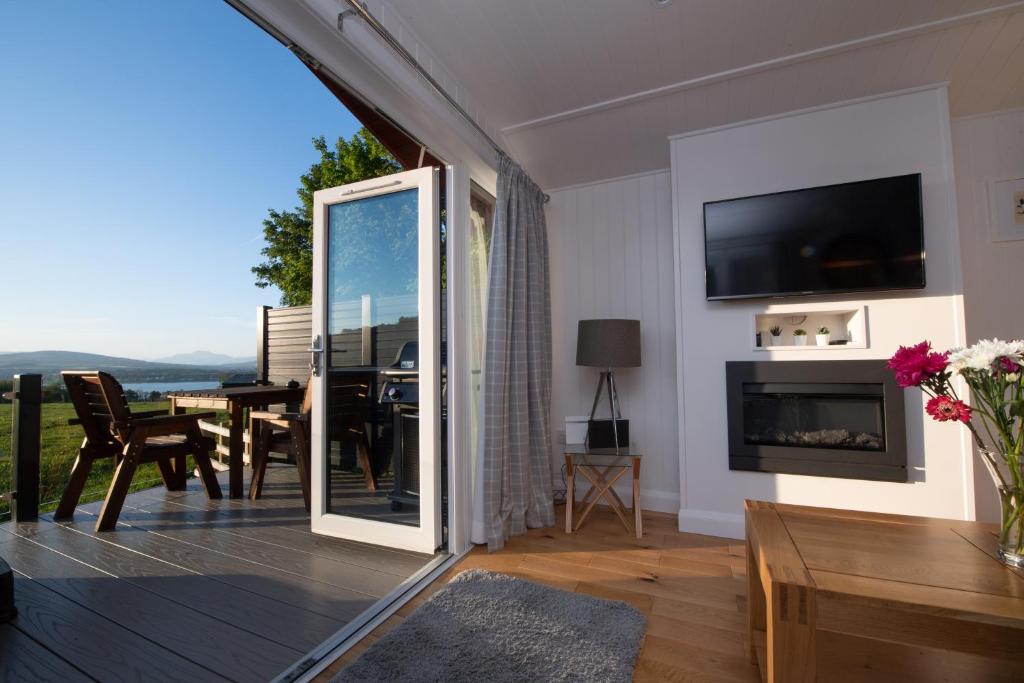 una sala de estar con una puerta corredera de cristal que conduce a un comedor en Super King Lodge-Sleeps 2-HotTub-Sea View, en Langbank