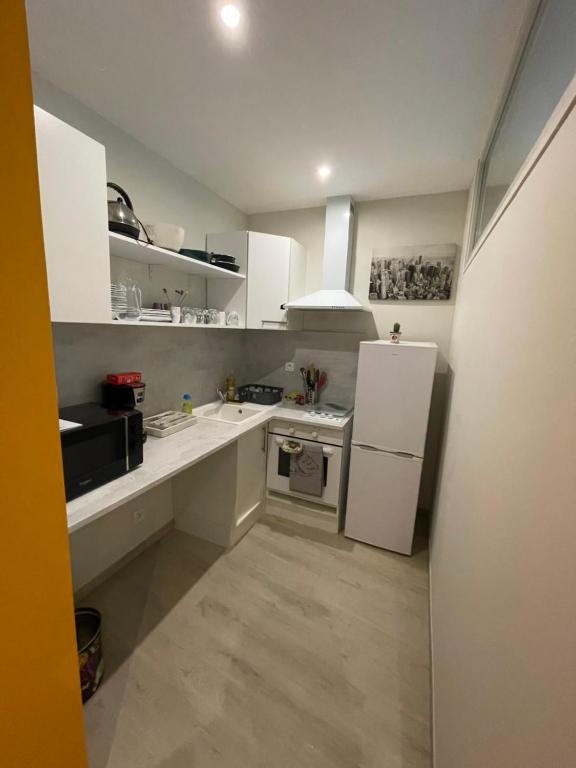 a small kitchen with white cabinets and a refrigerator at T2 hypercentre Libourne 5 min St Emillon in Libourne