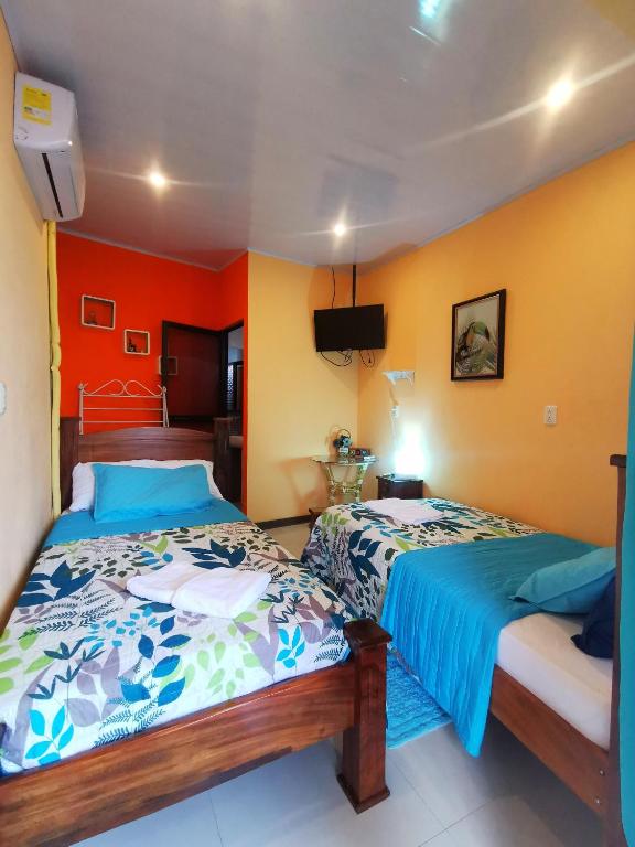 Dos camas en una habitación con paredes naranjas. en Cozy Sudio#1, 5min Beach & 1 hour Liberia Int ARPTO, en La Cruz