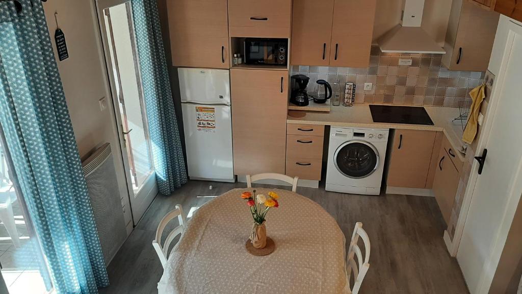 une cuisine avec une table avec un vase de fleurs dessus dans l'établissement Maison de vacances 300 m de la mer proche forêt, à Saint-Hilaire-de-Riez