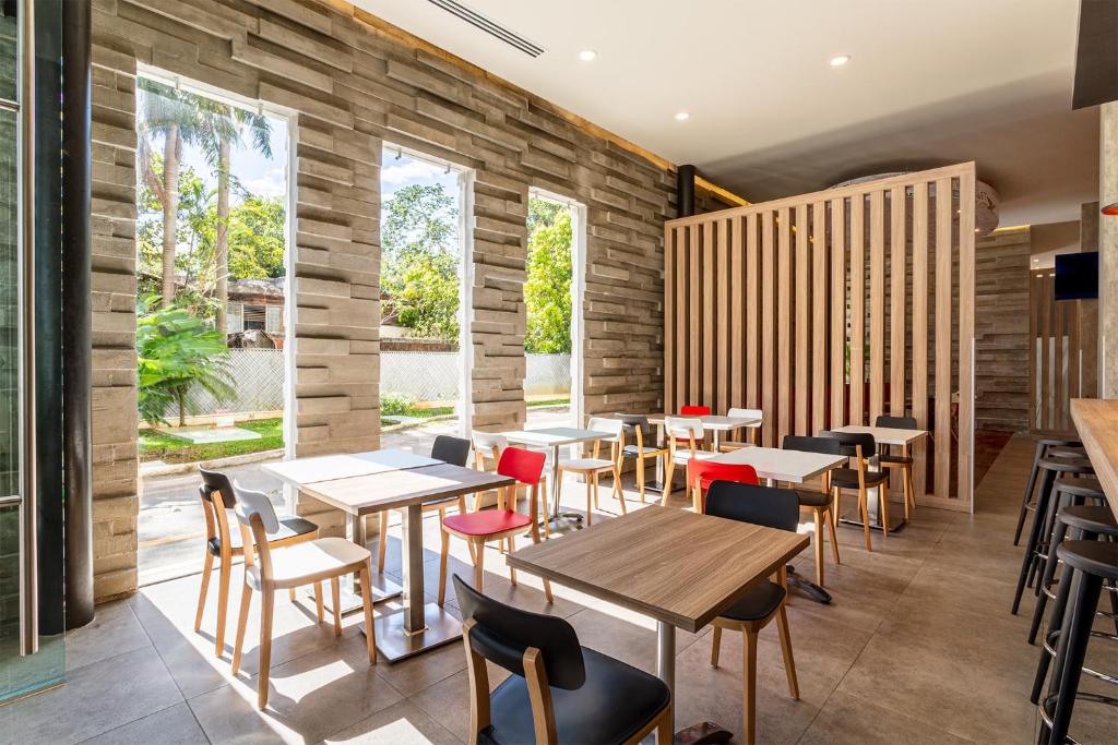 un restaurante con mesas y sillas de madera y ventanas grandes en Ibis Merida, en Mérida