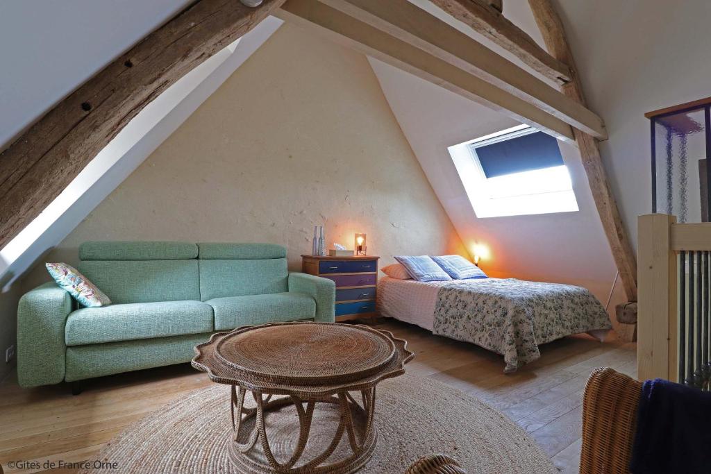 um quarto no sótão com um sofá verde e uma cama em La Dragonne, petite maison au centre de Bellême, jardin, cuisine équipée, vue forêt em Bellême