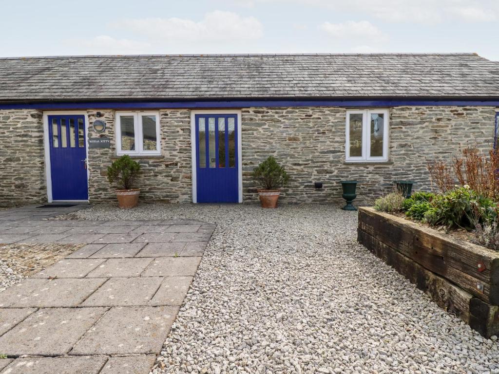 a stone house with blue doors and a courtyard at Wheal Kitty in Newlyn East