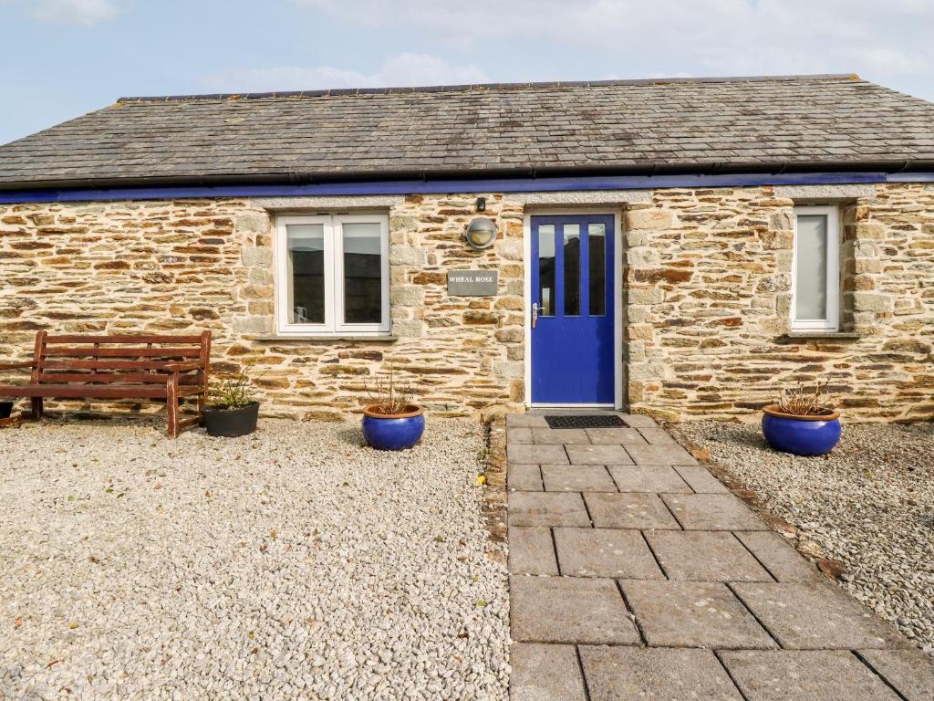 a stone cottage with a blue door and a bench at Wheal Rose in Newlyn East