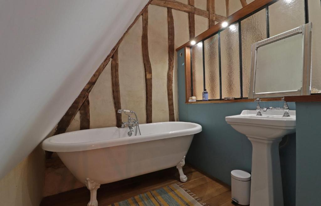 a bathroom with a bath tub and a sink at La Dragonne, petite maison au centre de Bellême, jardin, cuisine équipée, vue forêt in Bellême