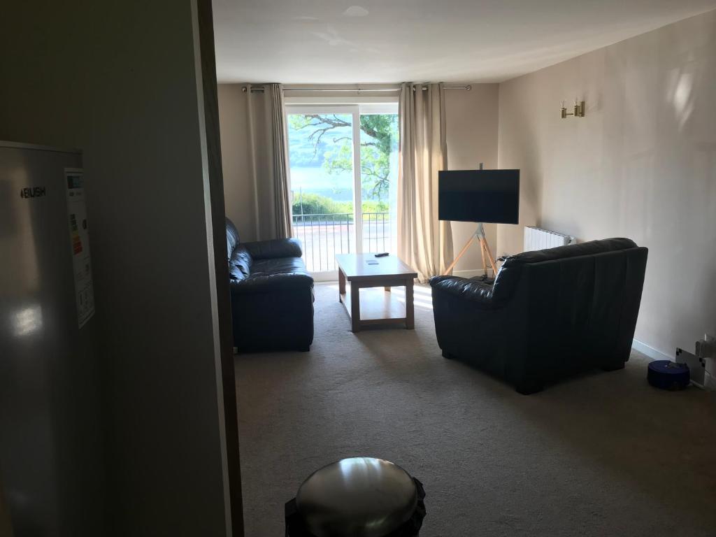 a living room with two couches and a television at Borrodale, one bedroom apartment with balcony and loch view. in Fort William