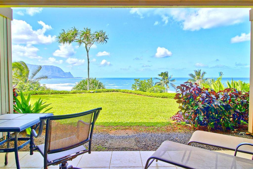 une terrasse avec une table et des chaises et l'océan dans l'établissement Pali Ke Kua 111, à Princeville