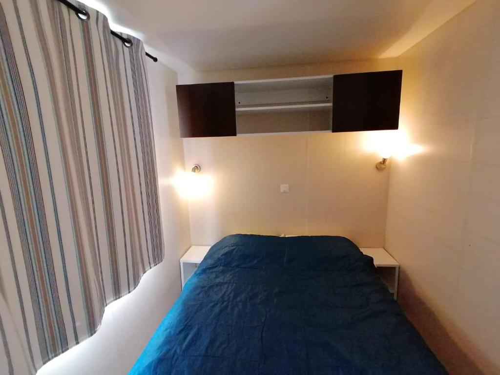 Un pequeño dormitorio con una cama azul y una ventana en Le domaine des iscles, en La Roque-d'Anthéron