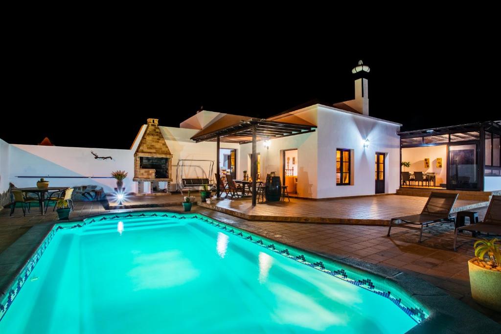 a swimming pool in front of a house at night at Eslanzarote Acoruma House, Super Wifi, Heated Pool in Güime