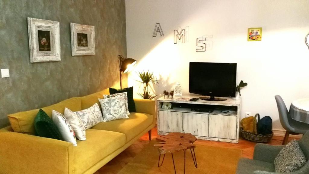 uma sala de estar com um sofá amarelo e uma televisão em The sunset Lisbon flat em Lisboa