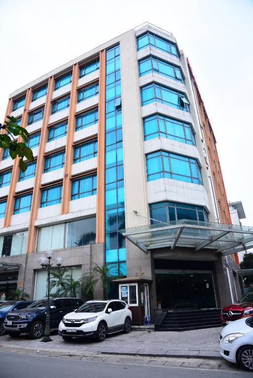 a large building with cars parked in front of it at TQT Hotel in Hanoi