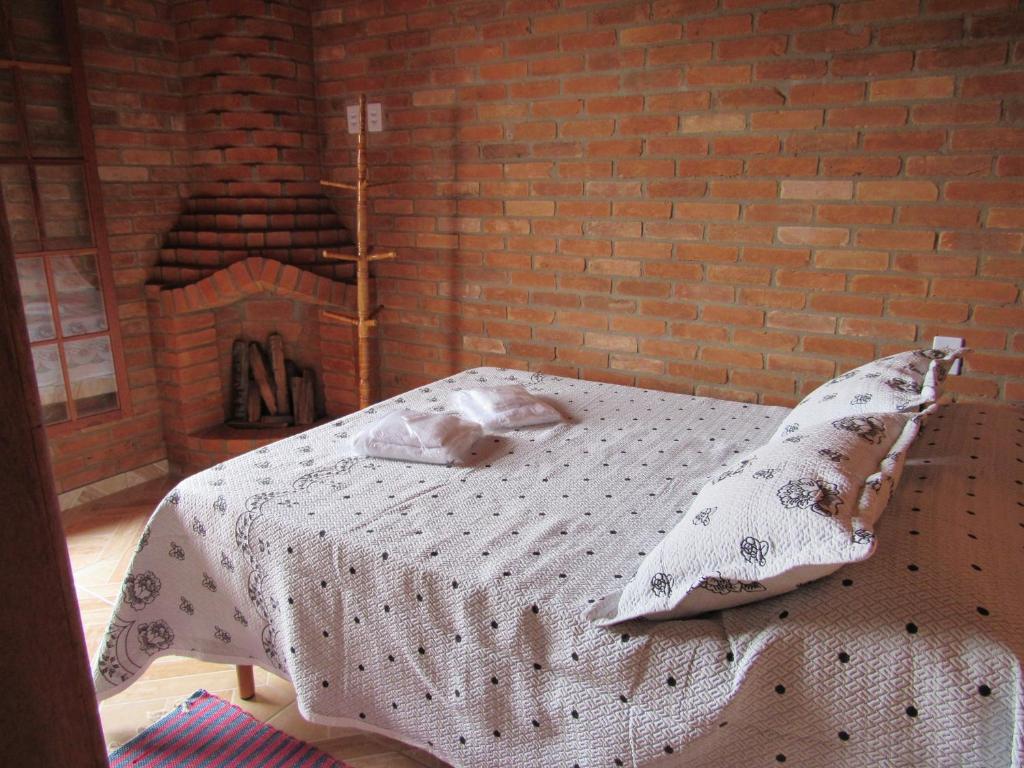 Cama en habitación con pared de ladrillo en CHALÉ Nativo R do Céu nº 106, en Conceição da Ibitipoca