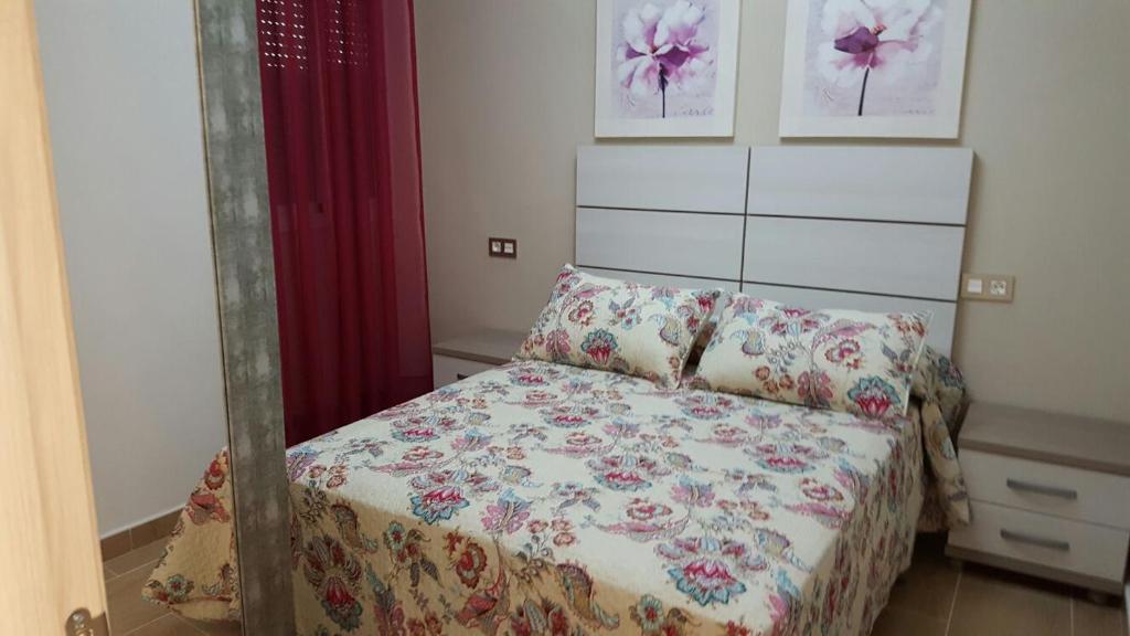 niewielka sypialnia z łóżkiem i czerwoną zasłoną w obiekcie Apartamento Loyola Tania w mieście Conil de la Frontera