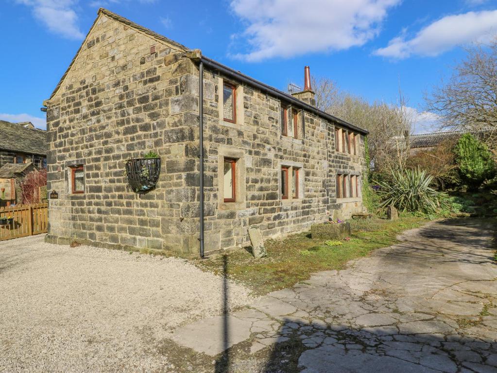 an old stone house with red windows on a street at Stables Cottage in Todmorden