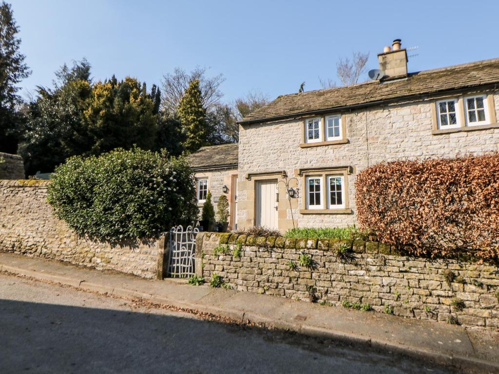 a brick house with a stone wall and a gate at Rose Cottage in Bakewell