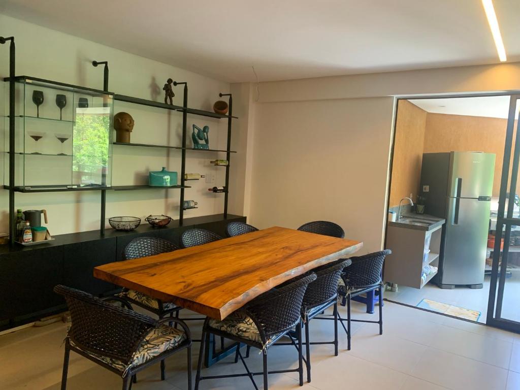 uma sala de jantar com uma mesa de madeira e cadeiras em Apartamento família com 3 quartos no Eco Resort Carneiros em Tamandaré