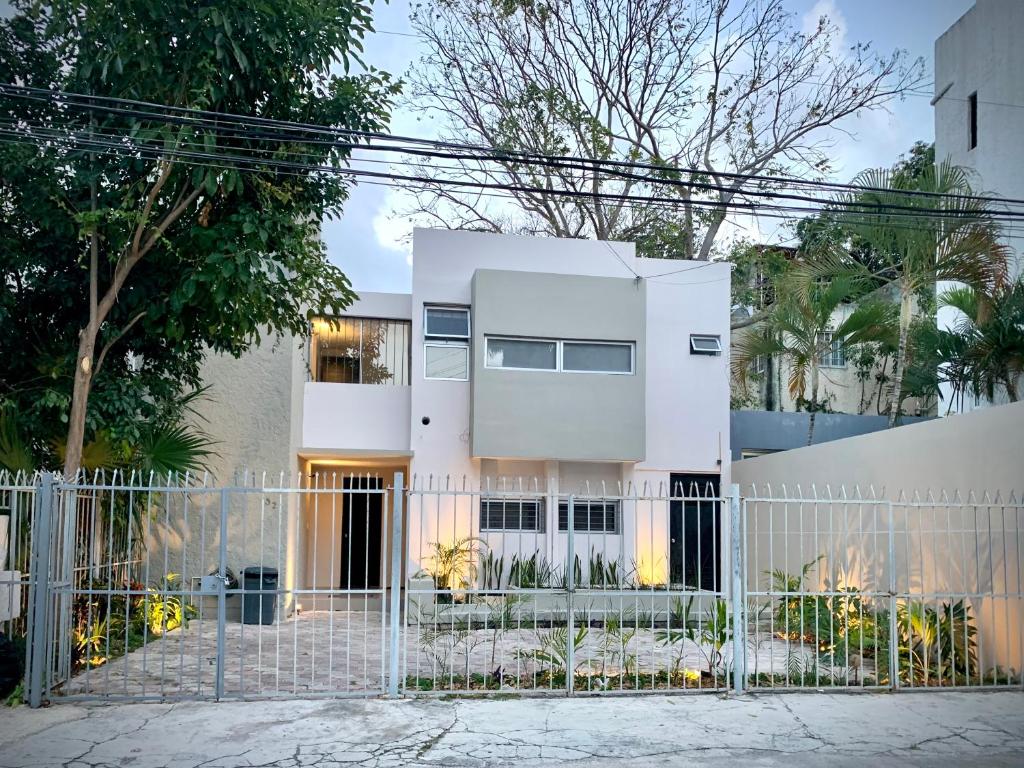 uma casa branca com uma cerca à frente. em Océano Studios em Cancún
