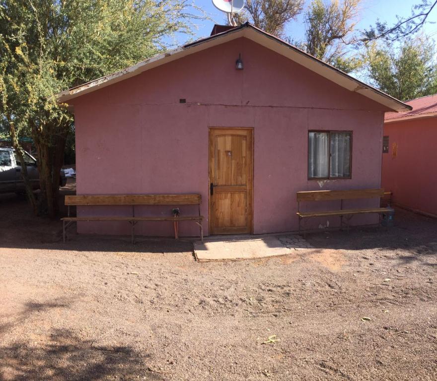 a pink building with two benches in front of it at Cabañas rústico in San Pedro de Atacama