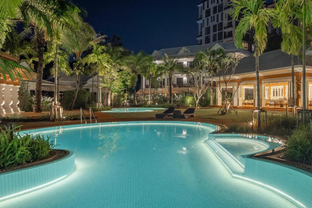 a swimming pool at night with a hotel in the background at The Pe La Resort, Phuket - SHA Extra Plus in Kamala Beach