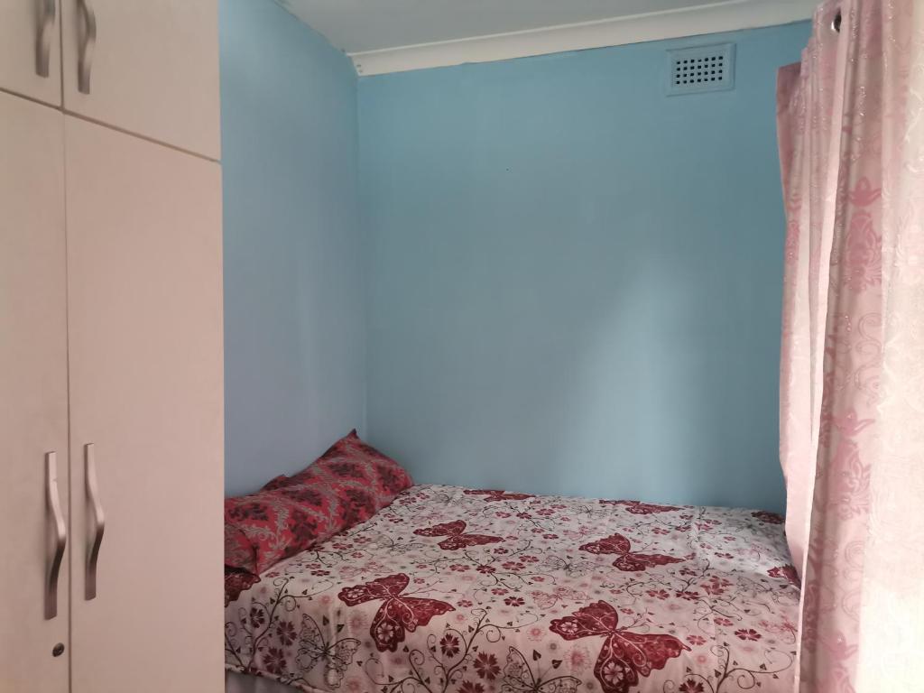 Un dormitorio con una cama con una colcha floral. en JackyCom, en Durban