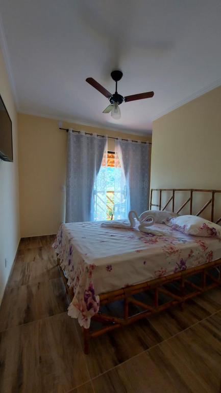 a bedroom with a bed with a fan and a window at Pousada Camping dos Ypês in Guapimirim