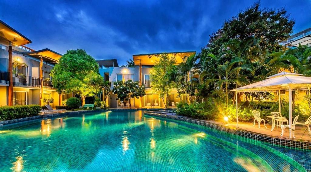 - une piscine avec un parasol en face d'une maison dans l'établissement Paeva Luxury Serviced Residence SHA, à Bang Bo