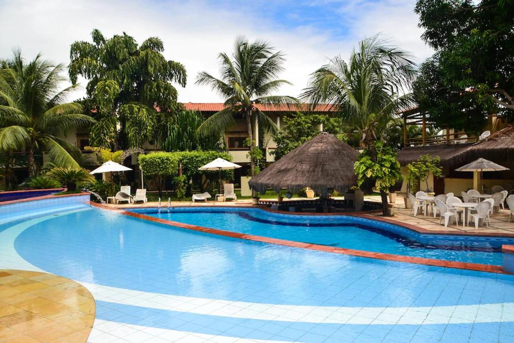 ein Swimmingpool mit Liegestühlen und Sonnenschirmen in einem Ferienresort in der Unterkunft Apartamento Studio - Solar Pipa in Pipa