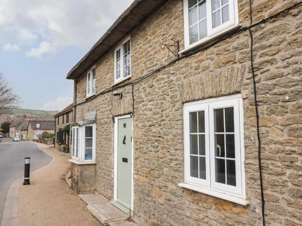 a stone house with white windows and a white door at River Cottage in Burton Bradstock
