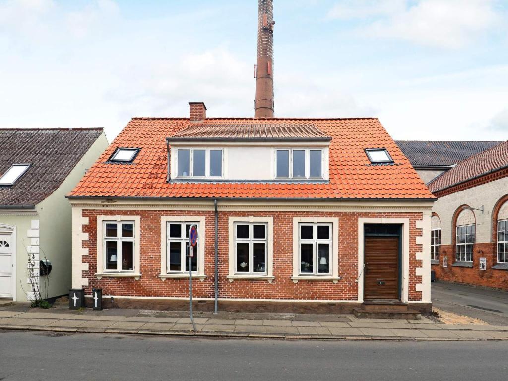 een stenen huis met een oranje dak en een schoorsteen bij 16 person holiday home in Rudk bing in Rudkøbing