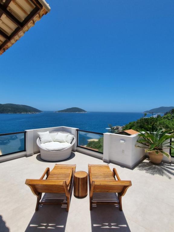 a patio with two benches and a view of the ocean at Casa Corazul in Arraial do Cabo