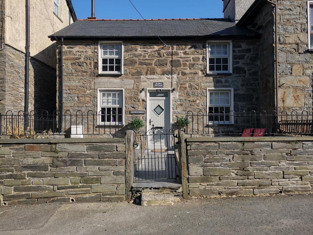 a stone building with a white door and a fence at Yr Hen Dy Capel in Blaenau-Ffestiniog