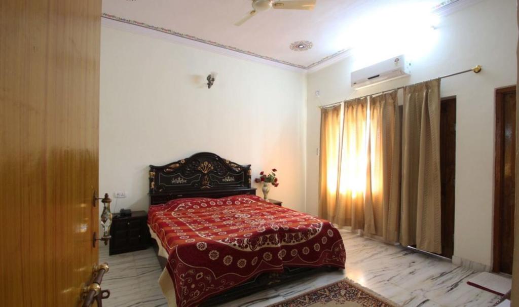 a bedroom with a bed with a red blanket and a window at Hotel New Park in Pushkar