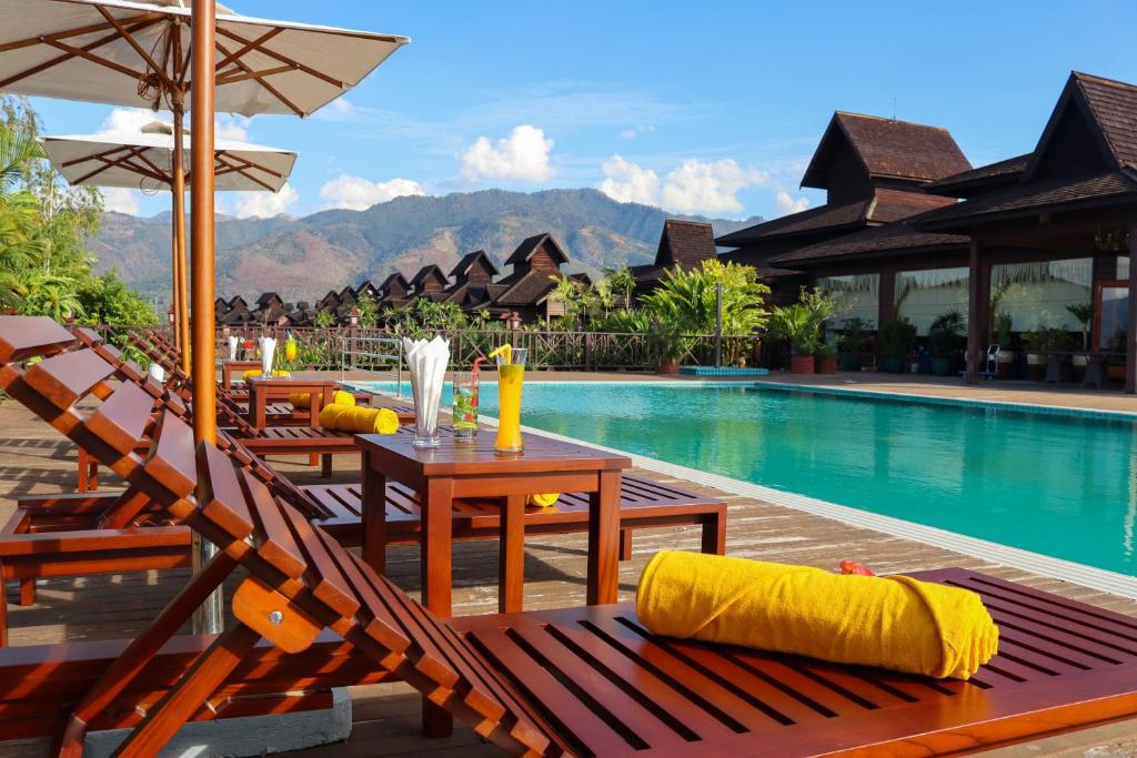 een resort met een zwembad en een tafel en stoelen bij KMA Inle Hotel in Nyaung Shwe