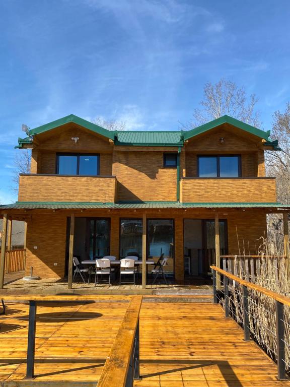 uma grande casa de tijolos com um deque de madeira em Lake River House Ada Bojana em Ulcinj