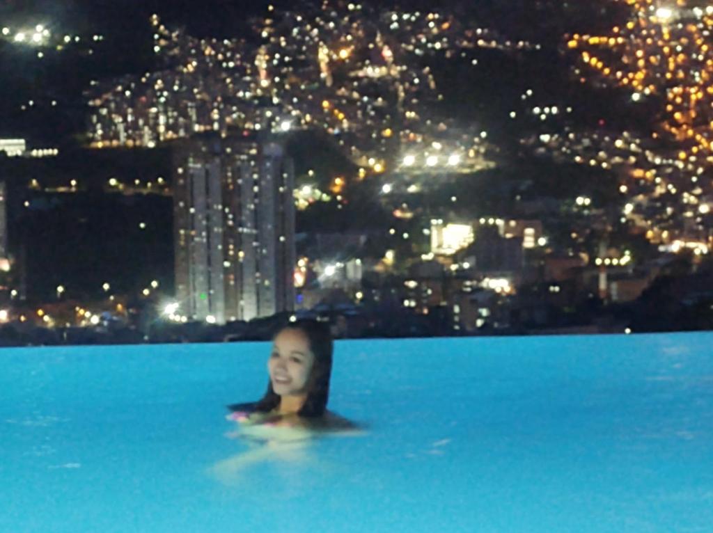 Una donna in una piscina con una città sullo sfondo di penthouse a Bello